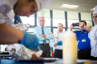 Jeff Brady (with tie), Campus Dining and Shops' executive director, and CDS staffer Ryan Rodenhaus watch while Bronek Lis plates the entrée. Photographing the scene is Ray Kohl, director of marketing.