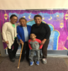 Alumna (right) poses with family in front of the Aladdin movie selfie wall at a Movie Night