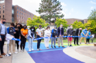UB students, staff, faculty and administrators cutting a ribbon to inaugurate the Progress Pride Paths display in Knox Quad outside of the Student Union. Photographer: Meredith Forrest Kulwicki