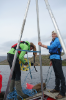 UB geology PhD student Allison Cluett (left) and UB geology undergraduate Kayla Hollister work on the researchers’ pontoon boat in Greenland. The boat includes a coring platform used to collect cylindrical samples of lakebed mud. Credit: Anna McKee