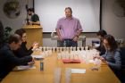 Jason Benedict, assistant professor of chemistry and crystal competition organizer, stands at the head of the table as the judging gets underway.