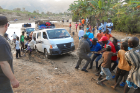 Haitians help free a van that got stuck in the mud on the other side of the river.