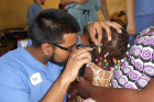Syed Samad, a second-year pharmacy student, uses an otoscope to examine the ears of a young girl.