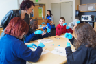 A Genome Day volunteer oversees students as they conduct their experiments.