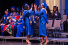 Student speakers Deidree Golbourne (left) and Yanava Hawkins congratulate each other as they pass onstage.