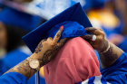 A student dons her cap before the College of Arts and Sciences morning commencement in Alumni Arena.