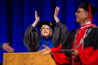 Robin Schulze, dean of the College of Arts and Sciences, claps while President Satish K. Tripathi presents student awards during the College of Arts and Sciences morning commencement in Alumni Arena.