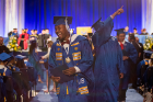 A graduate smiles broadly as he returns to his seat after receiving his diploma. 