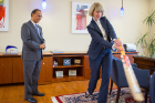 President Satish K. Tripathi looks on as incoming Chancellor Kristina Johnson takes a swing with a cricket bat.