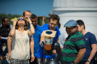 Physics student Alok Mukherjee (right, wearing hat) photographs the eclipse from the roof of Fronczak Hall. He shows his setup to John Cerne (bright blue shirt), professor of physics.