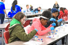 Tapestry Charter School eighth-graders Mara Quinn (green jacket) and Nyrelle Simpson work on extracting their DNA. Photo: Nancy J. Parisi