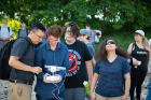 Students look on as Le Wang (left) and Nathan Dubinin prepare to launch the drone.