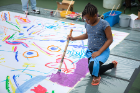 A young girl contributes her talents to a large community painting.