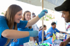 Natalie Lamb, a biochemistry graduate student, holds a test tube for a community member to see at the GEM table. 