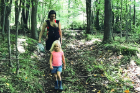 Katie McClain-Meeder hikes through the woods with her daughters Flora (in baby carrier) and Charlotte.