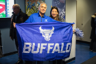 Marc Adler, president of the School of Management Alumni Association, displays a Bulls flag. With him is Smaranda Stan McNerney, associate head coach for the women's tennis team.