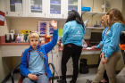 Give Kids A Smile Day has expanded its services beyond oral health care to include eye exams and screenings for hearing loss. Finn Everhardt raises his hand during his hearing assessment as (from left) Fina Young, Emily Kam and Brie Tross administer the test.
