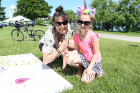 Kristin Brandt, a teaching artist with Young Audiences of Western New York, and Scarlett Pfender, 5, looking splendid in a unicorn headdress, invite other children to take part in their collaborative painting.