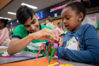 UB environmental design student and Imagine LaSalle volunteer Nofel Sohail helps a child with her design.