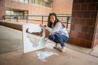 Rachel Lim uses chalk and a stencil to fashion the Bulls' spirit mark during Spirit Week activities. Photo: Douglas Levere