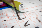 Students practice their calligraphy skills on a water-writing cloth. The water appears black when brushed on the cloth.