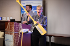 Wendy Quinton, winner of the 2018 Life Raft Debate and this year's MC, holds the winner's prize: a rowing oar that lists the names of the winners of the eight previous debates.