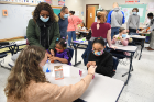 Pharmacy student Annie Kurdziel helps Erika Garcia (in purple shirt), age 5, a kindergarten student at Sedita school, and fourth-grader Carlee Virgil (in black cardigan) make their slime with as much glitter and other accoutrements as possible.