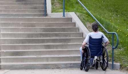 A person in a wheelchair is at the bottom of a flight of stairs. 