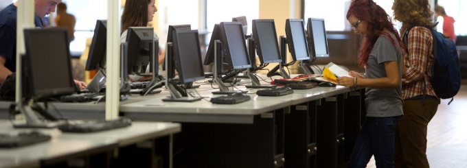Students standing at computer workstations. 