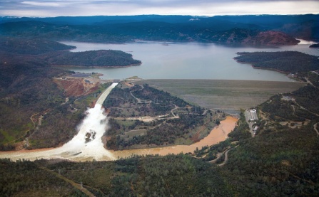 Zoom image: Aerial photo facing east, toward Oroville Dam and Lake Oroville, showing the damaged spillway with its outflow of 100,000 cubic feet per second. Image courtesy of Dale Kolke, California Department of Water Resources. Photo taken February 15, 2017. 