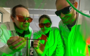 three people in a lab studying a sample. 