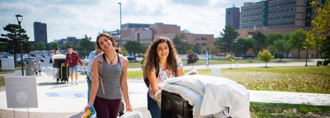 Students carrying goods into their residence hall. 