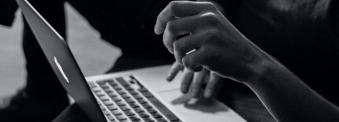Black and white photo of person typing on a laptop. 