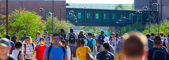 Large amount of students walking outdoors to get to class, on University at Buffalo's North Campus on a sunny day. 