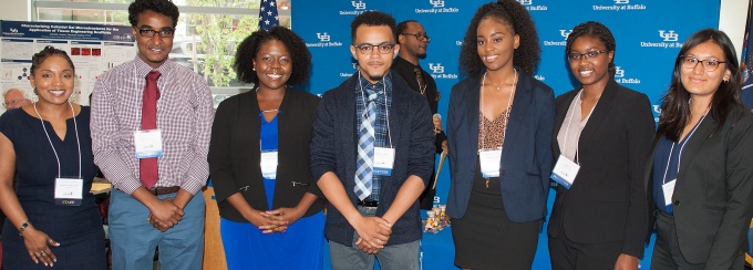 Student intern poster winners with Director in front of UB backdrop during the summer symposium. 