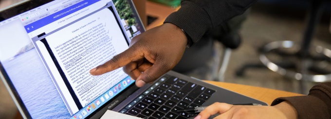 The hands of peers showing and guiding through a reading material on a computer. 
