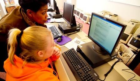 Faculty member helping a student at a computer. 