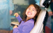 child smiling in dental chair. 