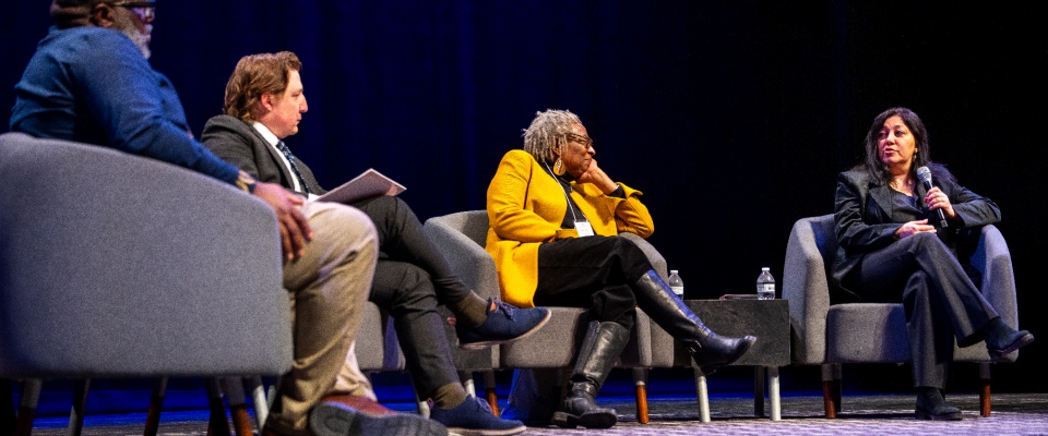 Rectangle logo with rainbow images of people holding hands, and the words "Inclusive Excellence Summit" at the bottom, and "Living Our Commitment" written on the right side of the logo. 