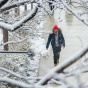 Student walking on snowy campus sidewalk framed by snow covered tree branches. 