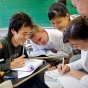 Group of students smiling at their desks. 