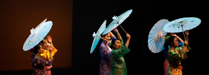 performers on stage with decorative umbrellas. 