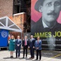 people posing in front of James Joyce mural. 