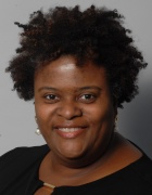 Letitia Thomas smiling in a headshot on a gray background. 