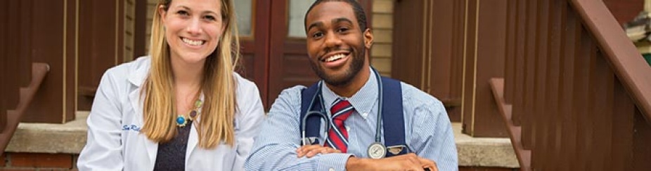 Two medical students smiling and sitting on steps outside/. 