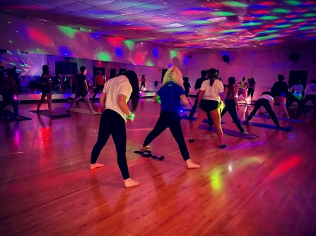 students participating in Glow Yoga in the Alumni Arena Dance Studio. 