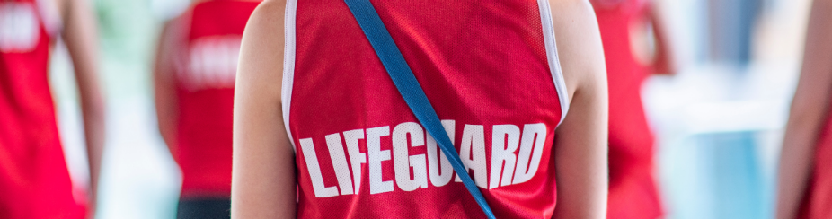 cropped photo of the back of a person wearing a red tank top that reads "LIFEGUARD". 