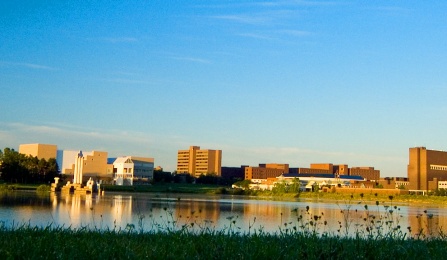 UB North campus during the summer - campus buildings in the horizon and lake in foreground. 