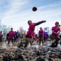A student leaps to bump the volleyball while in ankle-deep mud at Oozefest. 