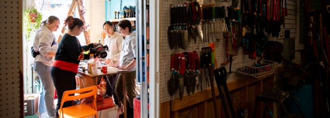 Three students and one worker discuss tool safety in The Tool Library workshop near UB's South Campus. 